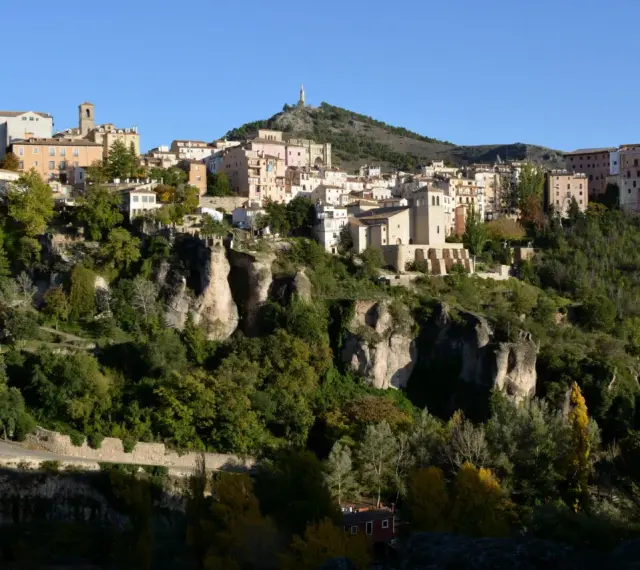 La ruta San Julián el Tranquilo en Cuenca: casas colgadas sobre riscos, vegetación frondosa y un cielo azul.