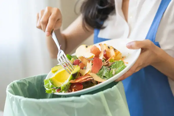 Persona separa restos de comida, como aguacate y cáscaras de manzana, para el reciclaje orgánico.