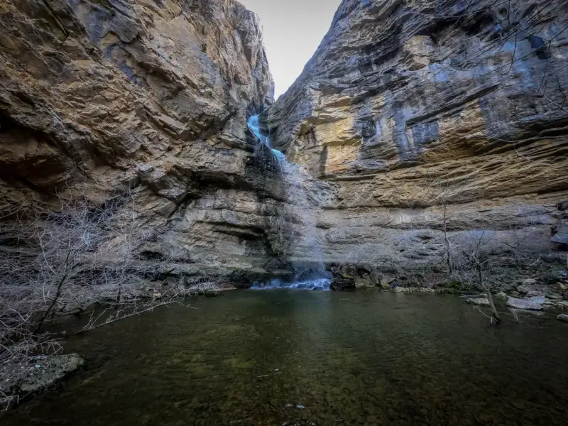 La cascada del Gollorio cae entre imponentes paredes rocosas, formando un estanque sereno.